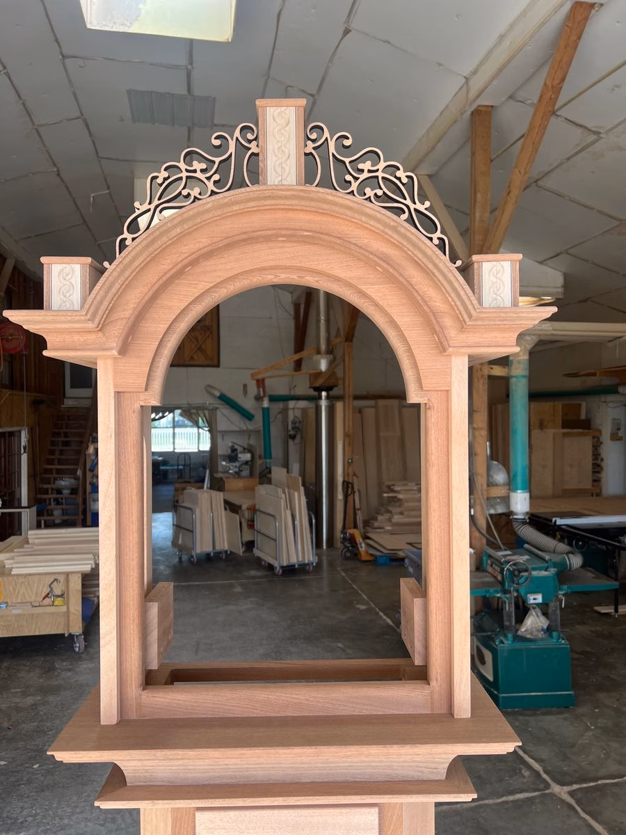 Unfinished mahogany clock bonnet with a hand-cut pierced fretwork crest and inlaid finial plinths