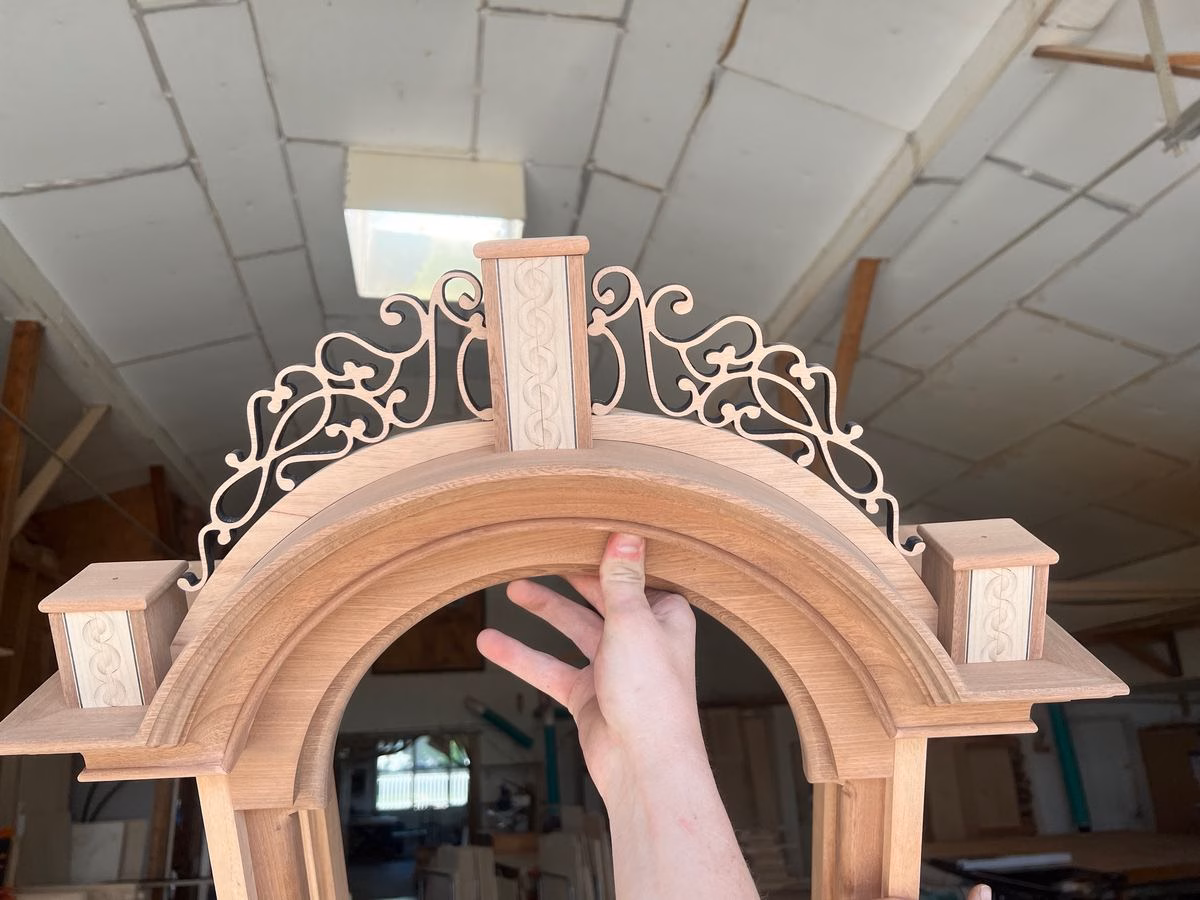 Close-up of the pierced mahogany crest with double lunette inlay on the finial plinths