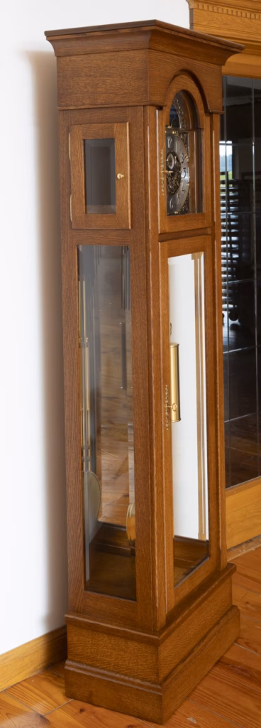 Angled view of a quarter-sawn white oak grandfather clock with hinged upper side door
